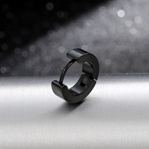 Close-up of minimalist black titanium steel huggie earring with polished finish