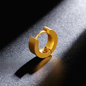 Macro detail of golden stainless steel huggie earring with brushed metal finish and shadows