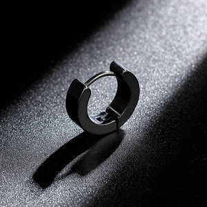 Close-up of matte black titanium hoop earring with snap-on closure on a textured grey base