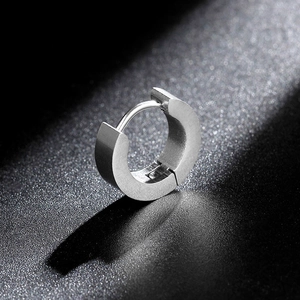 Macro shot of silver matte titanium steel huggie earring on a textured black background