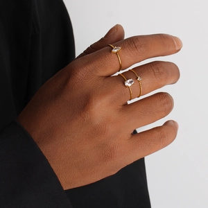 Three minimalist 18K gold-plated stainless steel rings set with zircon on female fingers