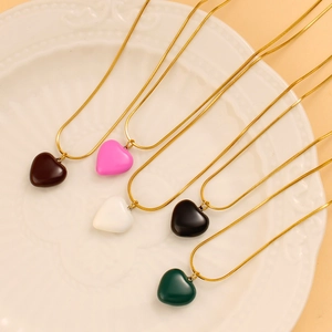 Detail view of five 3D heart necklaces in brown pink white black and green on a plate