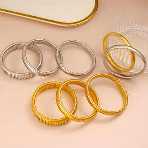 Detalle de pulseras elásticas doradas y plateadas con textura de malla de serpiente