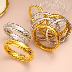 Primer plano de pulseras tubogas elásticas de oro y plata con textura de metal estriado