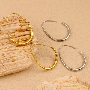 Detailed view of teardrop hollow earrings in 18K gold and silver polished stainless steel