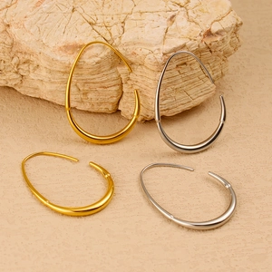 Detailed view of polished gold and silver teardrop hoop earrings on natural stone