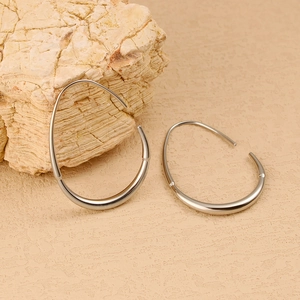 Polished silver teardrop earrings resting on a natural stone with a textured background