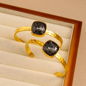 Detail of hammered 18K gold plated cuff bracelet with faceted square grey crystal