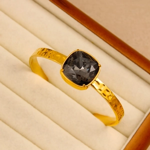 Macro detail of 18K gold hammered texture cuff bracelet with faceted square grey crystal