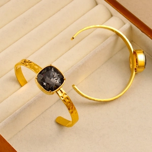 Detailed close-up of 18K gold plated C-shaped bangles with square faceted crystals
