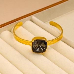 Detail of 18K gold plated C-shape cuff featuring a faceted black square crystal inlay