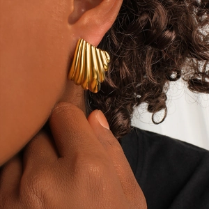 Elegant gold-plated shell-shaped earrings with striped texture worn by a model