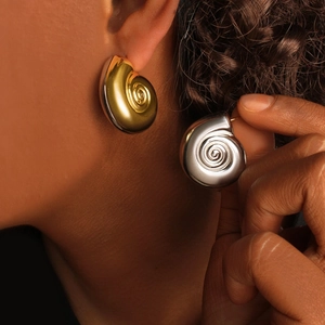 Close-up of modern spiral C-shaped stainless steel stud earrings in gold and silver
