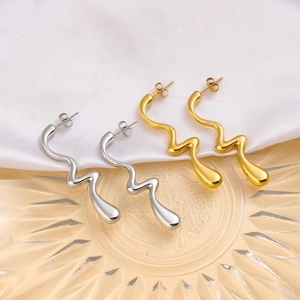 Detalle de pendientes irregulares de oro de 18 quilates y plata sobre seda blanca