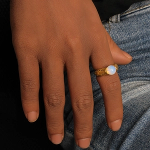 Detail of vintage gold ring with white opal stone and embossed texture on model