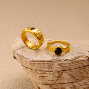 French vintage gold-plated rings with black stones and pearls on natural stone background