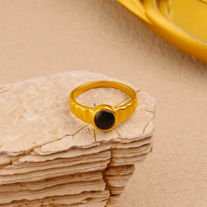 Detailed view of a vintage gold-plated ring with black oval stone on natural stones