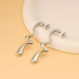 Detalle macro de pendientes plateados ondulados con diseño de metal líquido moderno