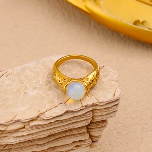 Detail of vintage gold ring with intricate engravings and white round moonstone gemstone