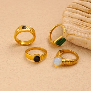 Macro view of gold vintage rings set with black stones and malachite on sandstone