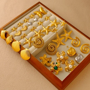 Detailed close-up of ocean-themed gold earrings with starfish and seashell shapes in a box