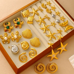 Golden ocean series earrings featuring starfish, seashells, and pearls in a display case