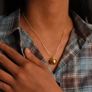 Detail view of 18K gold plated apple pendant necklace on a model with plaid shirt