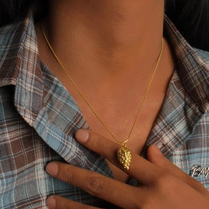 Detailed macro view of 18K gold plated stainless steel grape pendant necklace on a snake chain