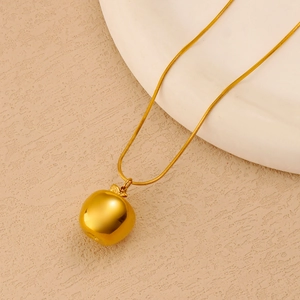 Polished gold snake chain necklace featuring a glossy apple pendant on a textured surface
