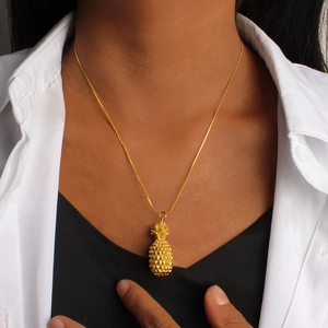 Close-up of a gold pineapple pendant necklace on a model with detailed texture