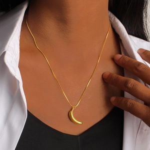 Close-up of a glossy gold banana pendant on a sleek snake chain necklace for women