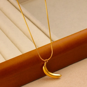 Detail of 18K gold plated banana pendant on a snake chain over a jewelry display box
