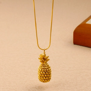 Close-up of golden pineapple pendant necklace with detailed 3D embossed metal texture