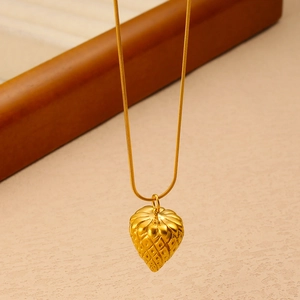 Macro shot of gold strawberry pendant on sleek stainless steel snake chain necklace