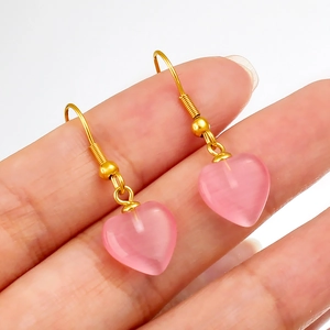 Détail de boucles d'oreilles cœur en pierre œil de chat rose avec crochets dorés