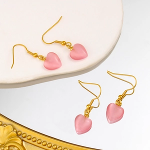 Détail de boucles d'oreilles cœur œil de chat rose avec crochets dorés texturés