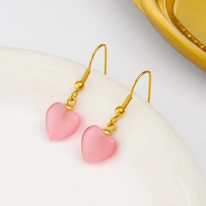 Boucles d'oreilles en pierre œil de chat rose et acier inoxydable doré sur un plat