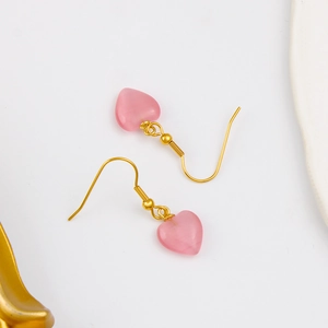 Boucles d'oreilles cœur en pierre œil de chat rose avec crochets dorés sur fond blanc