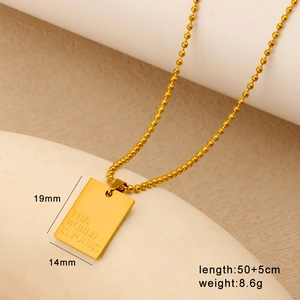 Dettaglio del ciondolo quadrato placcato oro 18K con incisione THE WORLD IS YOURS