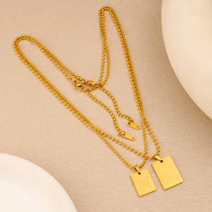 Dettaglio di ciondoli rettangolari placcati in oro 18K PVD con incisione More Self Love