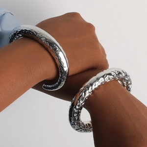 Brazaletes anchos en forma de C de plata pulida con relieve texturizado en muñeca