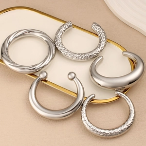 Detalle de cinco pulseras de acero inoxidable plateado con texturas martilladas y torcidas
