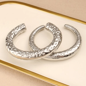 Detalle de pendientes de aro plateados con relieve de lava sobre un plato elegante
