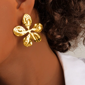 Elegant gold five-petal flower earrings with hammered texture on female model