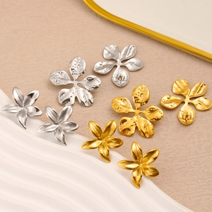 Detailed macro view of gold and silver five-petal flower earrings with hammered metal texture