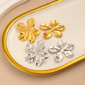 Detail view of 18K gold and silver textured flower earrings on a white ceramic plate