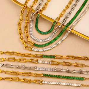 Detail of horseshoe link necklace and bracelet set with emerald green zircon in gold finish