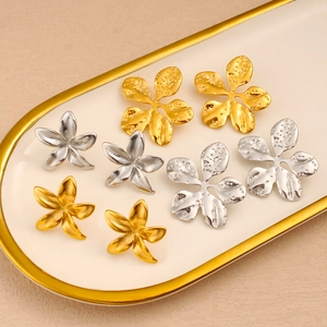 Detailed close-up of gold and silver flower earrings with textured petals on ceramic tray