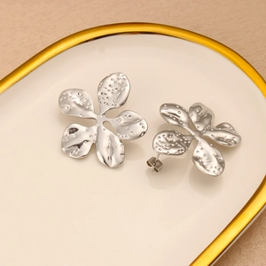 Detailed view of silver petal earrings with hammered texture on a porcelain dish