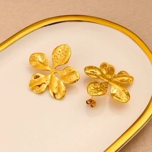 Detail of 18K gold plated flower earrings with hammer texture in a white ceramic dish